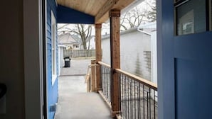 A covered porch with wooden beams and a metal railing, leading to a driveway. - Lauralee’s Legacy House-Minutes to Cedar Point (Sandusky)