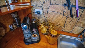 Une cuisine avec un mur en pierre, une machine à café, une bouilloire et un évier.