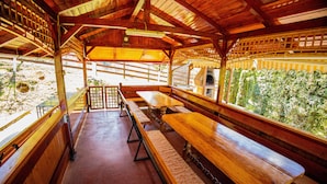 Un pavillon extérieur en bois, doté de bancs et offrant une vue sur la verdure.