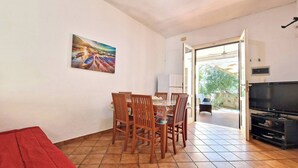 Uma área de refeições com mesa e cadeiras, uma televisão e um quadro na parede.