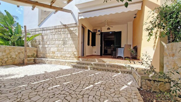 Um pátio com piso de pedra, parede de pedra e pérgola de madeira.
