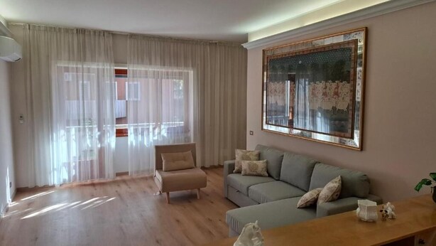 Un salon comprenant un canapé, un fauteuil, une table basse en bois et un grand tableau accroché au mur.