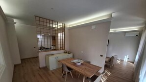 Une cuisine moderne avec une table à manger en bois, un petit îlot central et un four encastré.