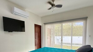A bedroom with a bed, a ceiling fan, a mounted TV, and a window with a view of the outdoors. - Casa Kai, a house with everything around it: mountains, beaches, tranquility... (Quebrada Ganado)