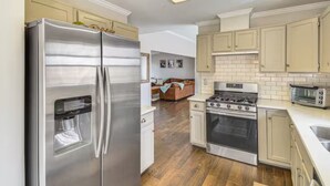 A modern kitchen with stainless steel appliances, a wood floor, and light-colored cabinetry. - Cozy Moose Grove: ski, hike, fish & relax (Fairplay)
