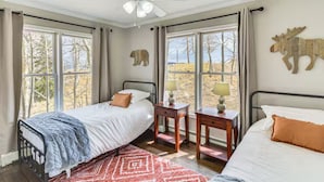 A bedroom with two beds, a ceiling fan, and large windows with curtains. - Cozy Moose Grove: ski, hike, fish & relax (Fairplay)