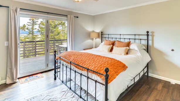 A bedroom with a bed, a ceiling fan, a nightstand, and a view through a sliding glass door to the outdoors. - Cozy Moose Grove: ski, hike, fish & relax (Fairplay)