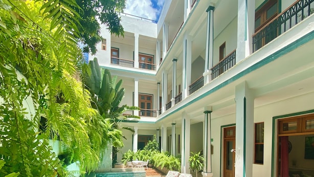 A multi-story building with a swimming pool, surrounded by lush greenery and potted plants. - Boutique Hotel Casa Grande, Dominican Voyage Familiar Suite, 2 BR (Santo Domingo)