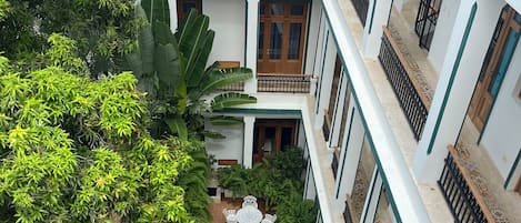 A multi-level hotel with a central swimming pool, surrounded by lush greenery and outdoor seating areas.