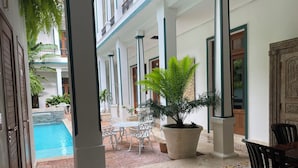 A hotel corridor with a pool, potted plants, and tiled flooring. - Boutique Hotel Casa Grande, Dominican Voyage Familiar Suite, 2 BR (Santo Domingo)