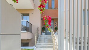 A modern building with a staircase leading to a balcony, potted plants, and a clear sky. - Casa Helone  (Kassandra)