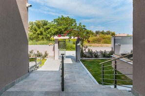 A modern outdoor staircase leading to a covered area with a view of greenery and a clear sky. - Casa Helone (Kassandra)