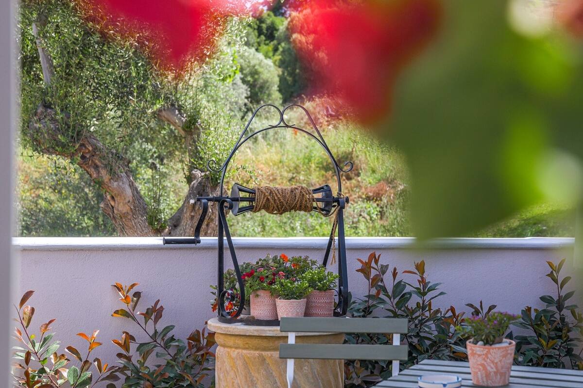 A balcony with a table, potted plants, and a hanging plant holder.