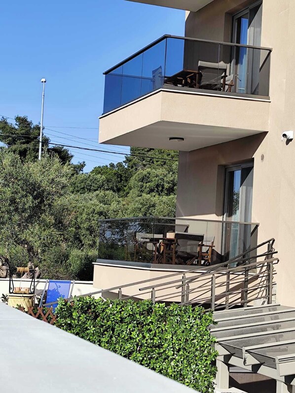 A modern multi-story building with a balcony, outdoor seating, and a staircase. - Casa Helone (Kassandra)
