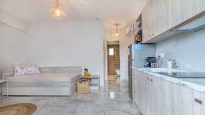 A modern bedroom with a bed, bedside table, and a small rug. The room has a wooden floor and a white wall. - Casa Helone  (Kassandra)