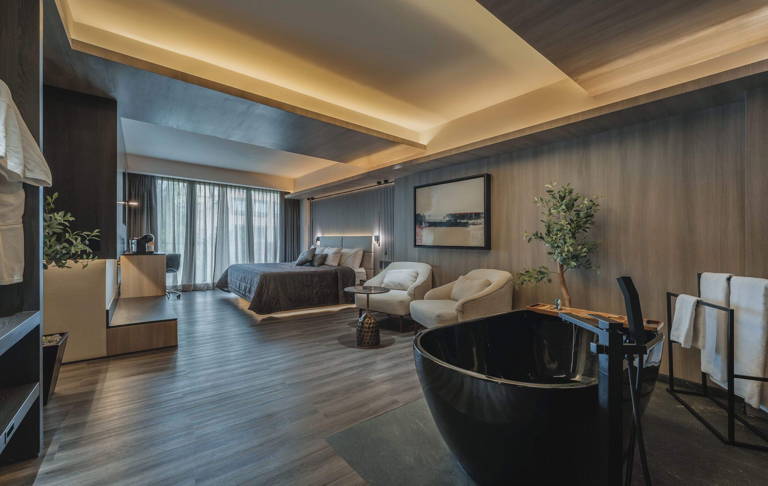 Habitación de hotel moderna con cama, zona de estar y un cuenco decorativo negro grande.