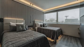Una habitación de hotel moderna con dos camas, un ventanal grande y vistas a la ciudad.