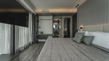 A modern hotel room with a large bed, a bedside table, a mirror, and a view of the city.