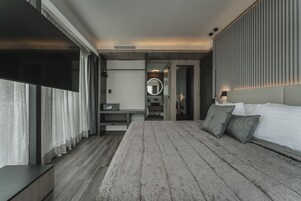 Habitación de hotel moderna con una cama grande, una mesita de noche, un espejo y vistas a la ciudad.