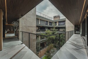 Un edificio moderno con un patio central, varios pisos y una combinación de materiales de concreto y vidrio.