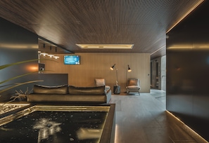 A modern interior with a reception desk, a sofa, a chair, and a water feature. - HOTEL CASA KAVIA (Mexico City)
