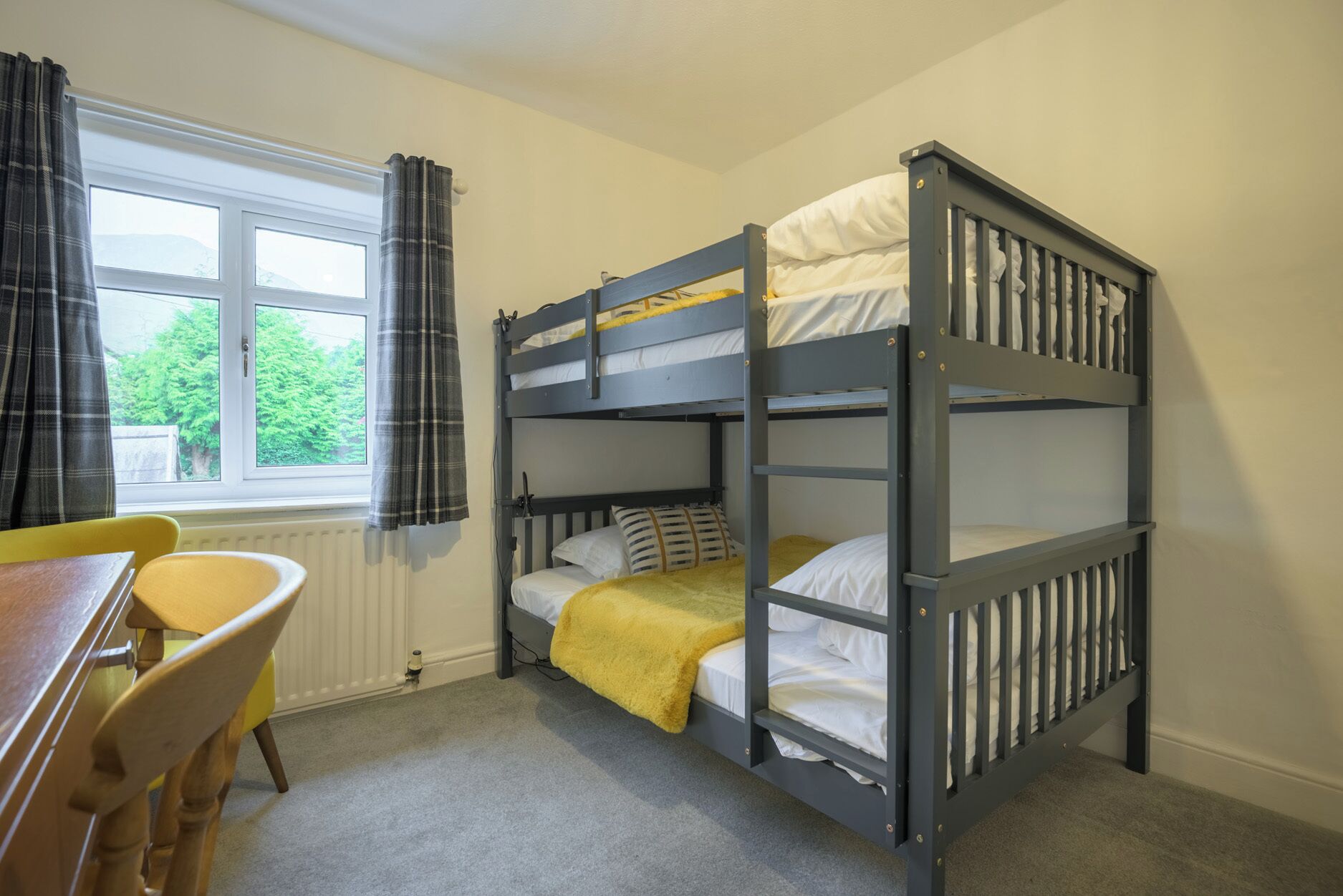 Une chambre avec un lit superposé, une fenêtre, un bureau et une chaise.