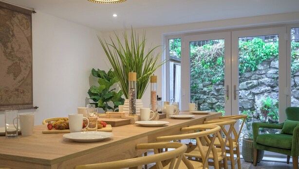 Un coin repas avec une table en bois dressée pour six personnes, entourée de chaises en osier.