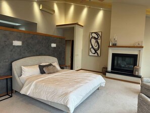 A modern bedroom with a large bed, a fireplace, and a minimalist decor.