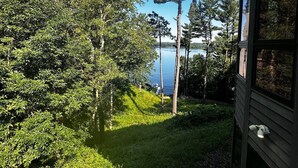 Vista de un lago rodeado de árboles, con un edificio de madera a la derecha.