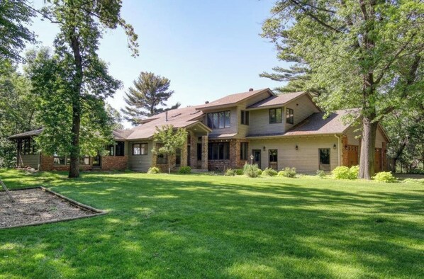 A two-story house with a front porch, a stone foundation, and a well-maintained lawn.