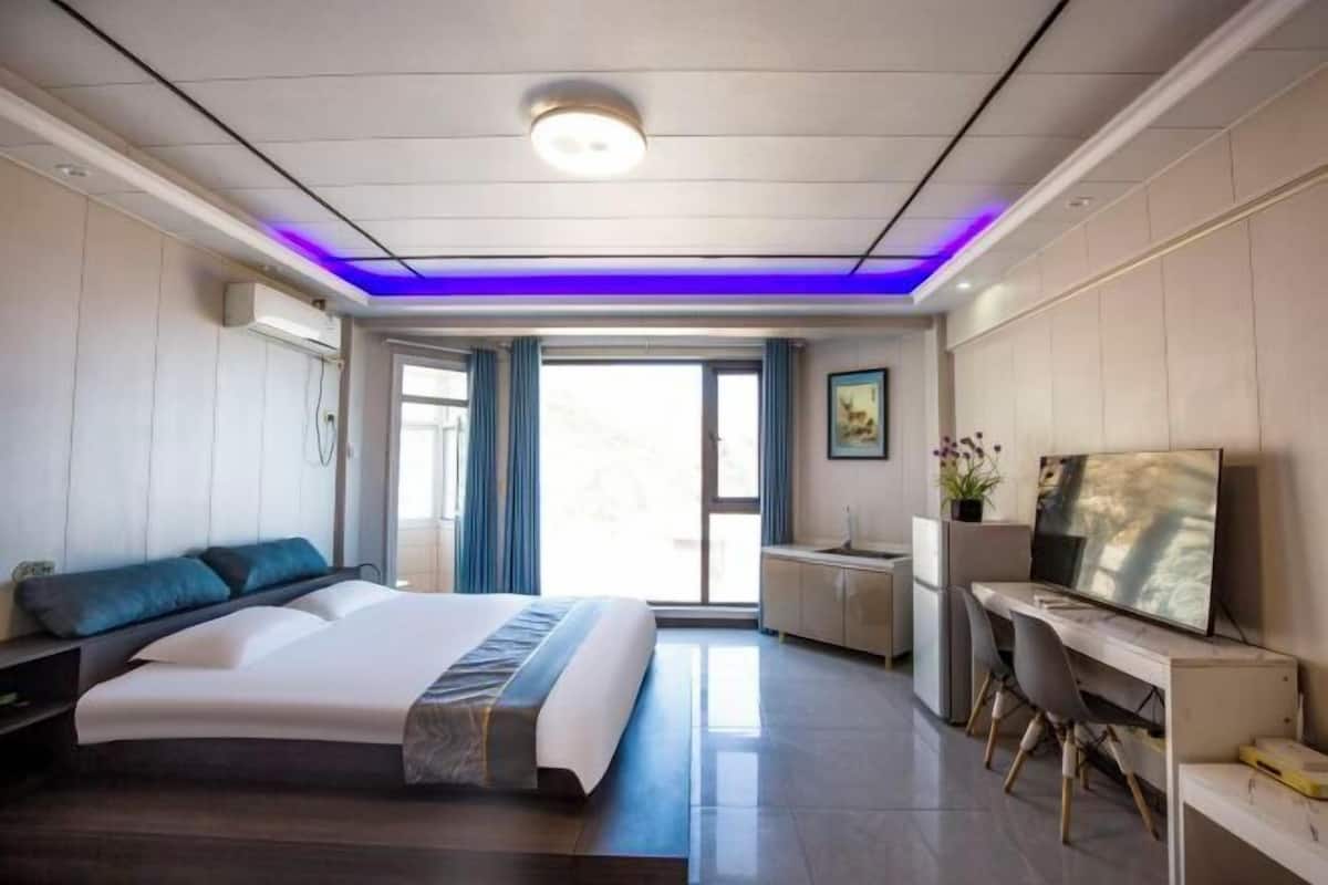 A modern hotel room with a large bed, a desk with a computer, and a TV.