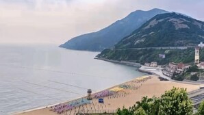 Vista costeira com praia, montanha e uma cidade.