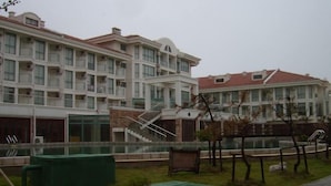 Um edifício residencial de vários andares com varandas, piscina e escadaria que dá acesso aos pisos superiores.