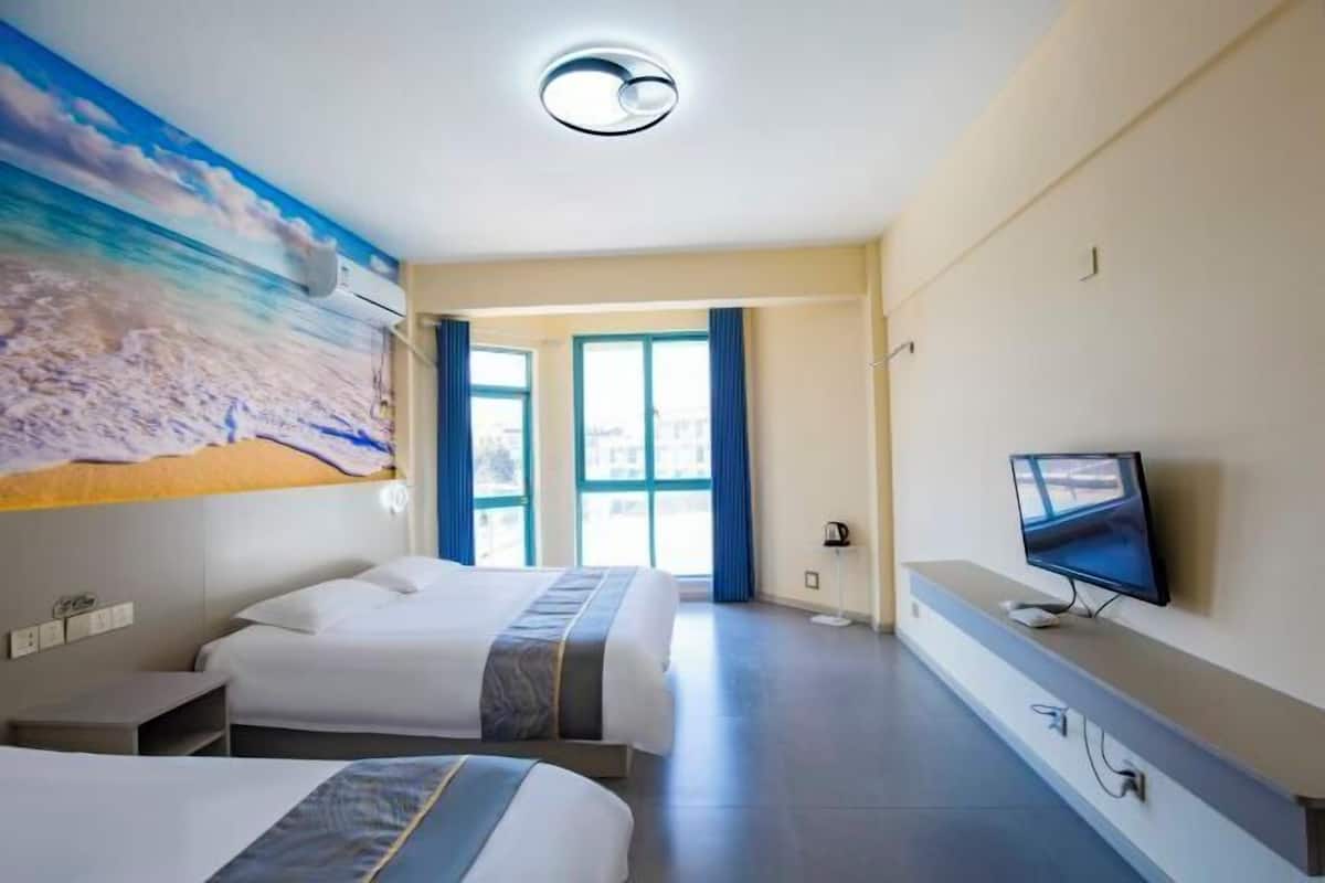 A hotel room with two beds, a television, a painting, and a window with curtains.
