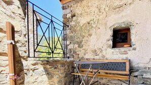Una habitación rústica de piedra con un banco de madera y una ventana pequeña.