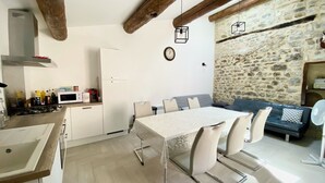 Una cocina moderna con comedor, pared de piedra y vigas de madera.
