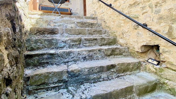 Una escalera de piedra que conduce a una puerta de madera con un ventanal pequeño.