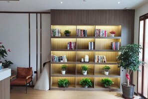 Un interior moderno con una estantería de madera, un sillón de cuero y plantas en macetas.