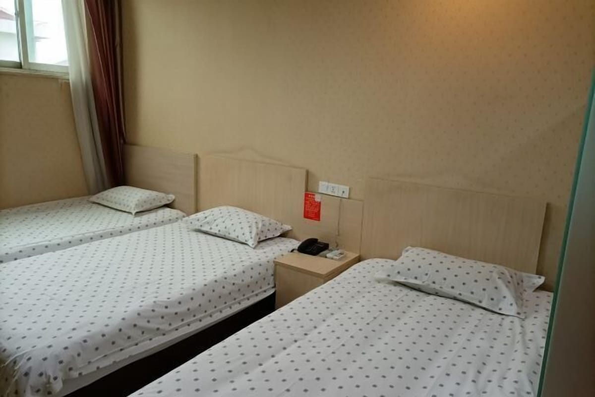 Ein Hotelzimmer mit zwei Einzelbetten, einem Nachttisch mit Telefon und einem an der Wand befestigten Lichtschalter.