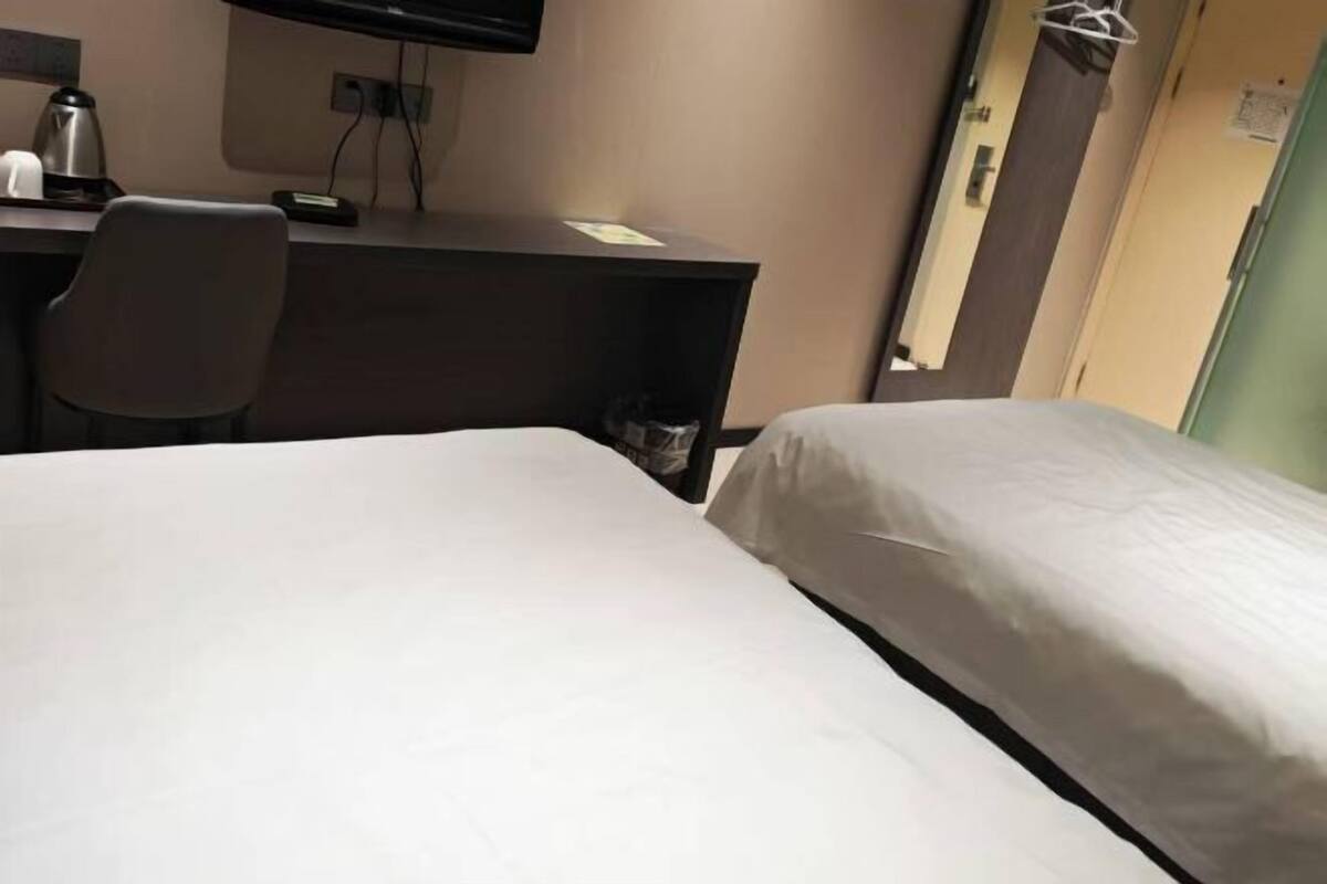 Una camera d'albergo con un letto, una scrivania con una sedia, un televisore e una porta.