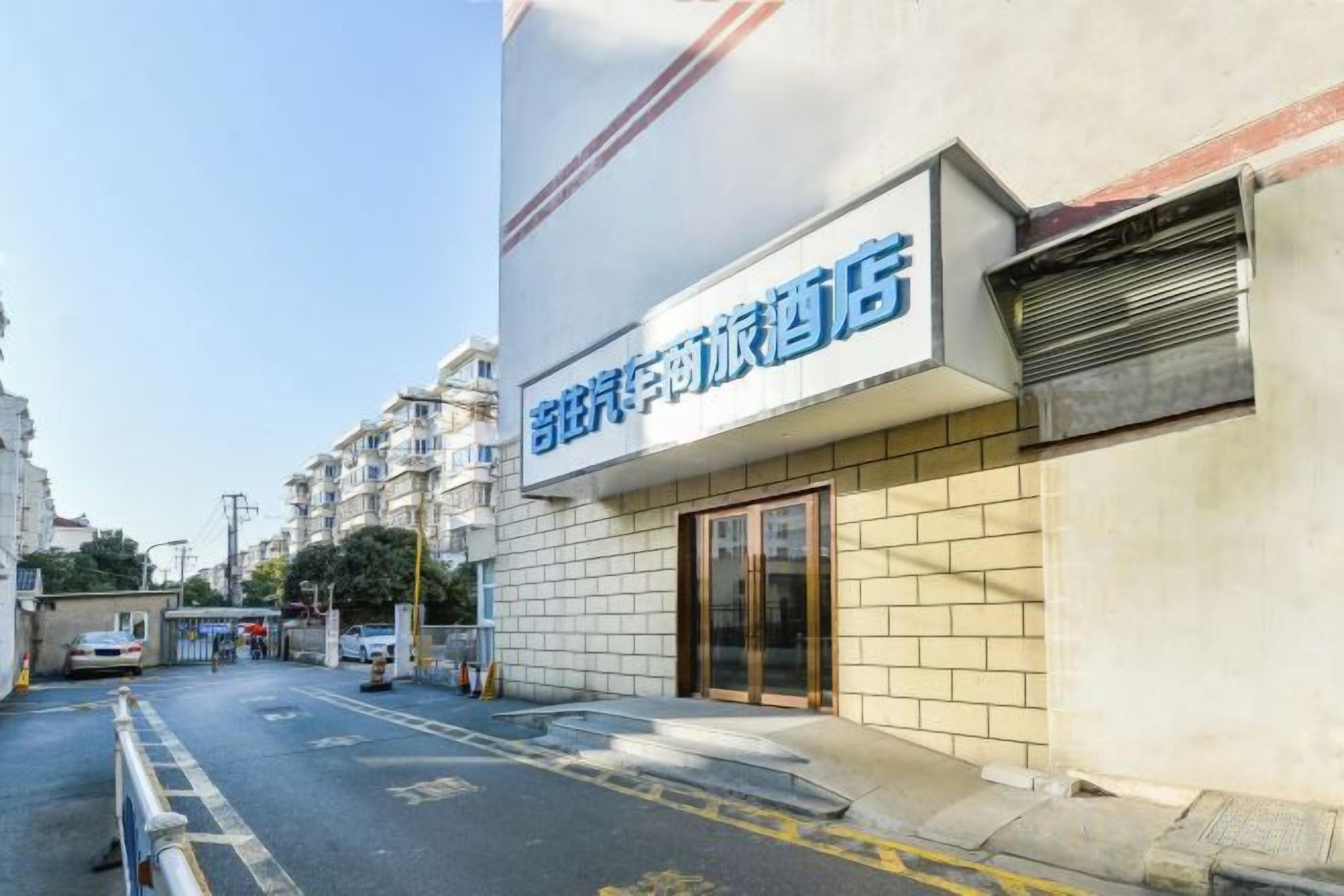 A hotel with a sign in a foreign language, a gated entrance, and a clear sky.