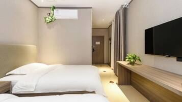 A hotel room with two beds, a TV, a plant, and a wooden console.