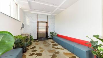 A modern lobby with a marble wall, a red bench, and a patterned carpet.