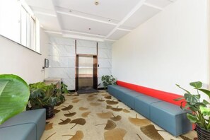 A modern lobby with a marble wall, a red bench, and a patterned carpet. - Jizhu Auto Business Hotel (Shanghai)