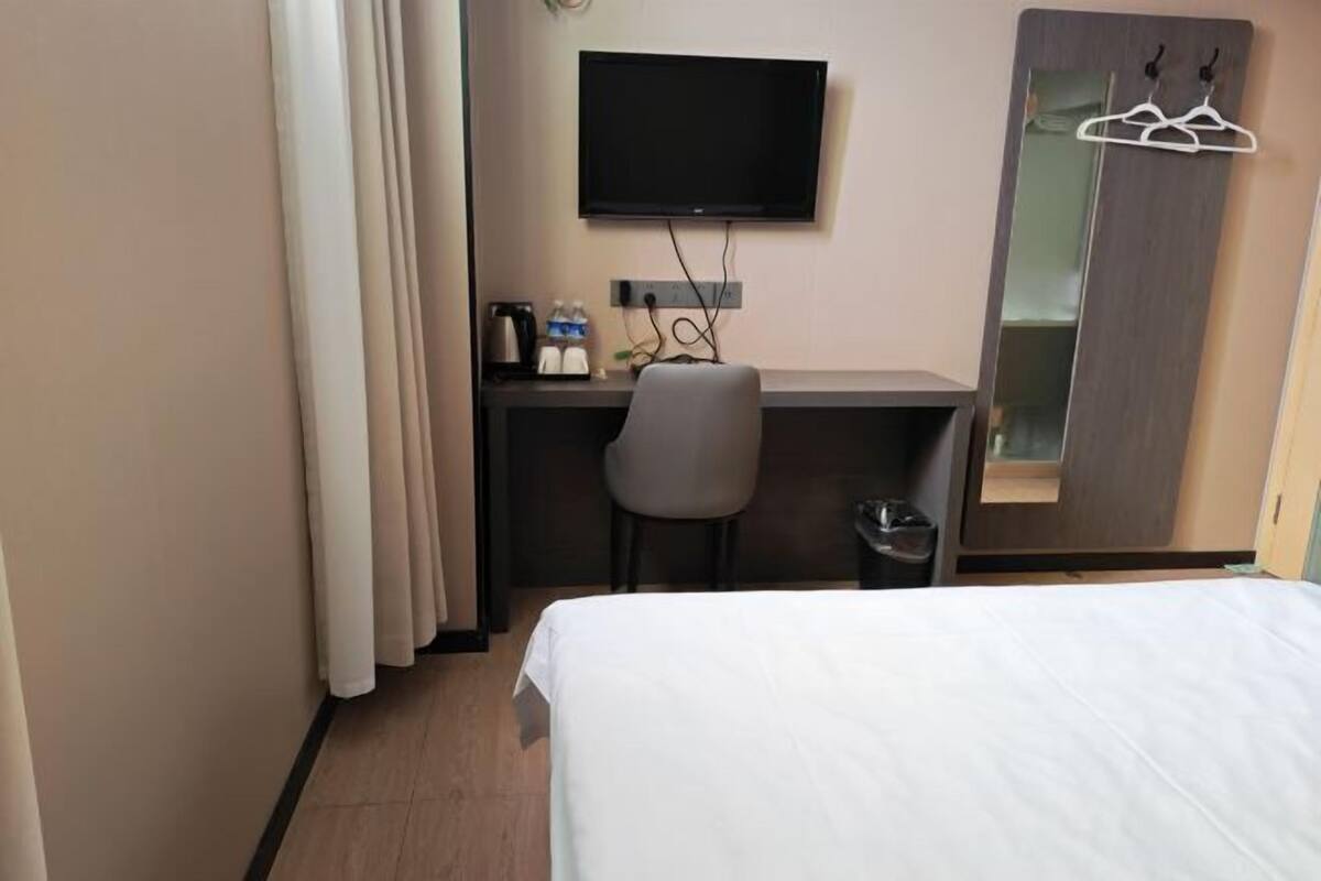 Una camera d'albergo con un letto, una scrivania con una sedia, una televisione e uno specchio.