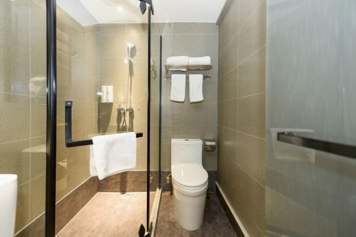 Ein modernes Badezimmer mit Duschkabine aus Glas, Toilette und Handtuchhalter.