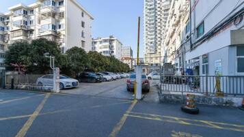 A residential street with parked cars, a gated entrance, and multi-story buildings.