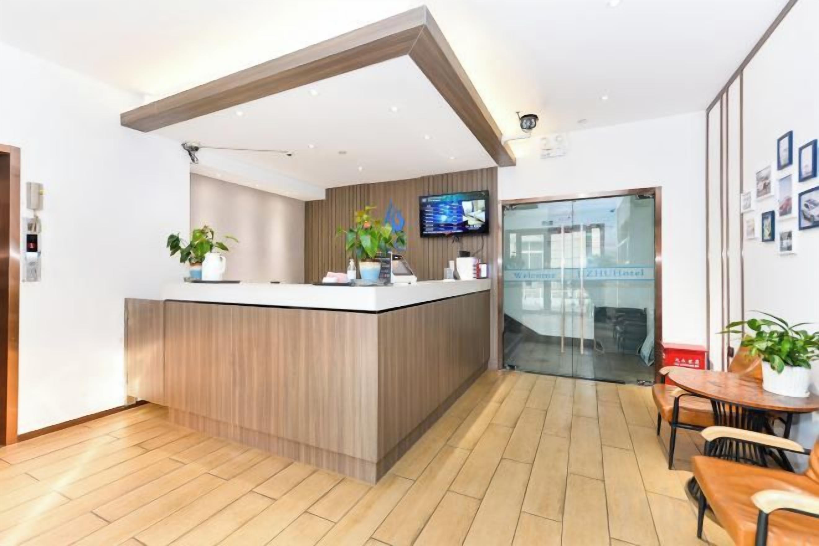 Un área de recepción con un mostrador de madera, un televisor de pantalla plana y una puerta de cristal que da al exterior.