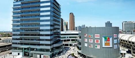 Un edificio moderno con varios pisos, un patio central y una fachada curva con anuncios.