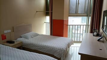 Une chambre d’hôtel avec deux lits, un bureau, une fenêtre donnant sur un beau paysage et un balcon.